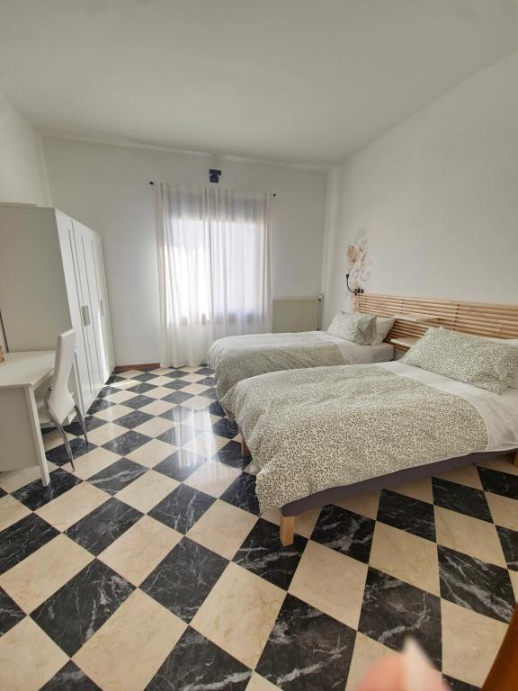 two beds in a room with a checkered floor at Il campazzo locazione turistica in Motta di Livenza