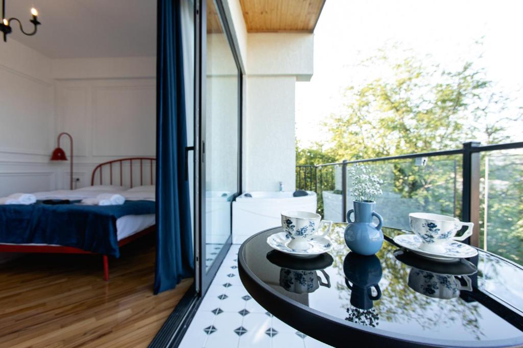une chambre avec un balcon avec un lit et une table en verre dans l'établissement 7 Doors - Boutique Apartments in Kutaisi, à Koutaïssi