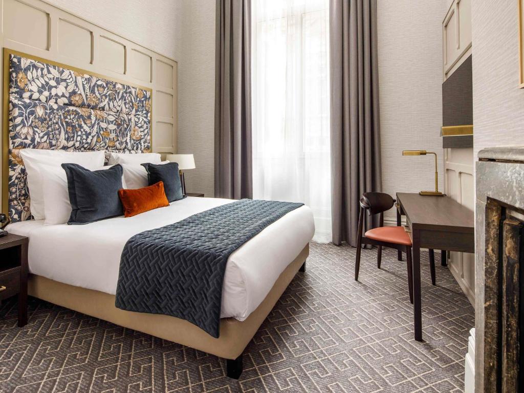 a hotel room with a large bed and a desk at The Municipal Hotel Liverpool - MGallery in Liverpool