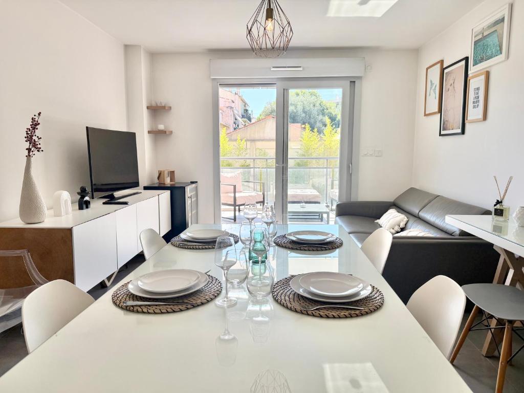a dining room and living room with a white table and chairs at T2 - piscine - garage privé - 5 min de Cannes in Le Cannet