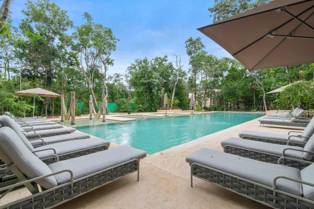a row of lounge chairs next to a swimming pool at Stylish 1BR Condo with Private Pool & Balcony in Tulum