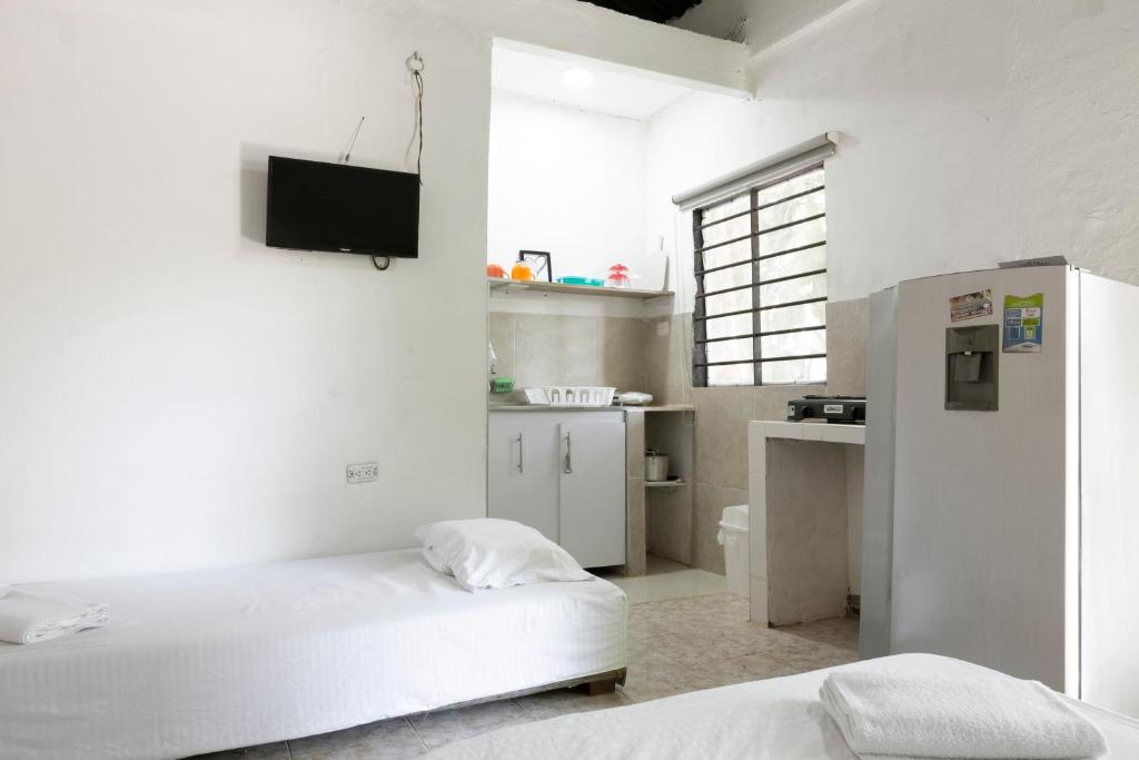 a white room with two beds and a tv on the wall at Hotel Villa Ivel in Turbaco