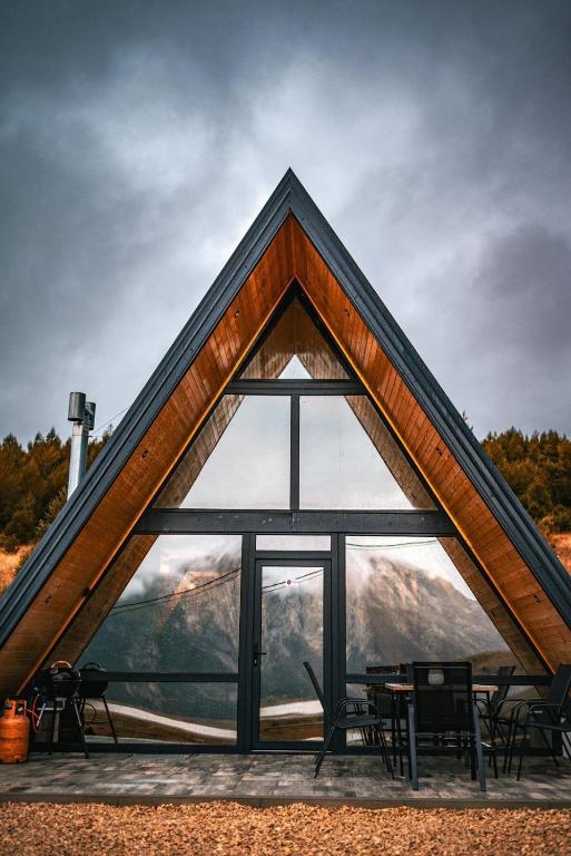 a triangular building with a large window with tables and chairs at Blidinje Lake House in Blidinje