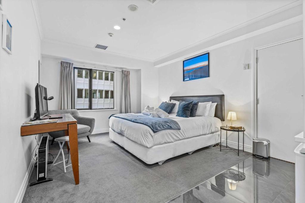 Un dormitorio blanco con una cama y un escritorio. en Cozy Room with King Bed, Gym and Pool Zodiak Stays, en Auckland