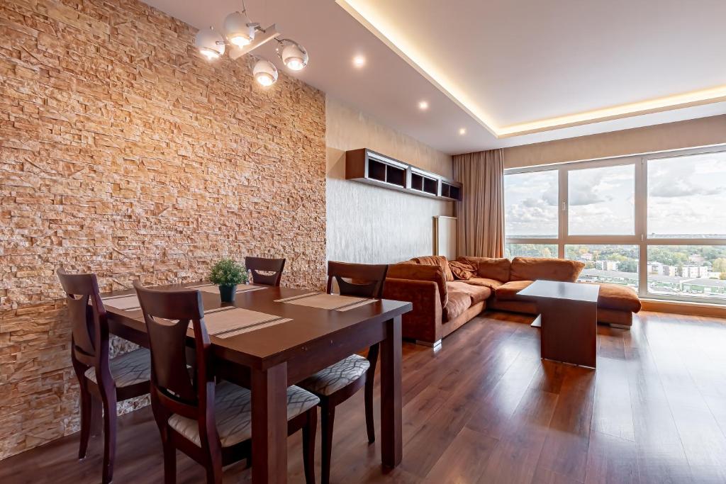 a living room with a dining table and a brick wall at Panorama Sky Apartment near Riga Airport & City Center in Rīga