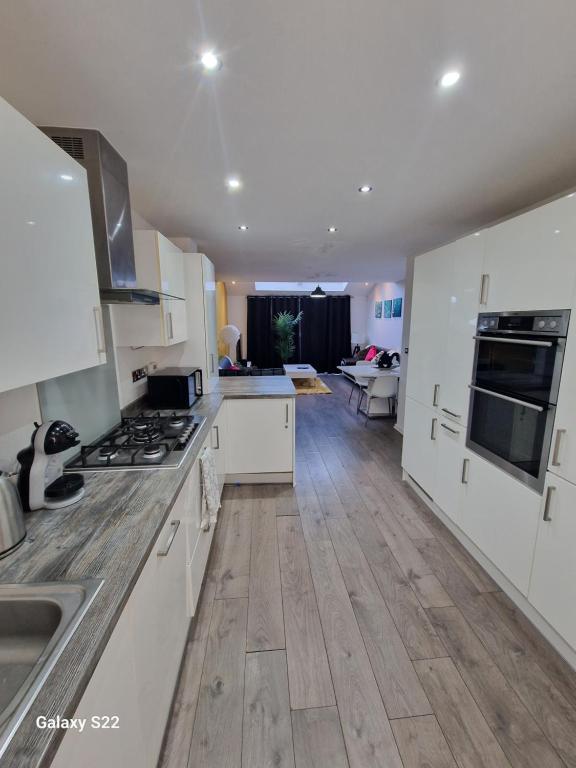 a kitchen with white cabinets and a wooden floor at Blue Haven 2 in Manchester
