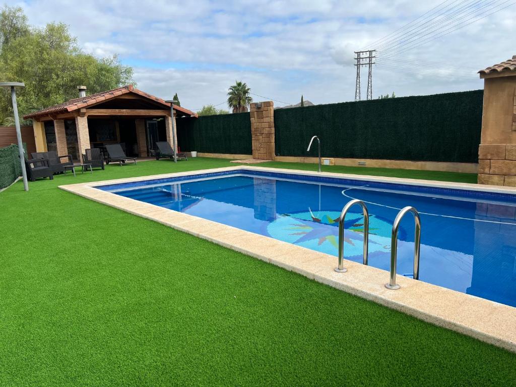 ムルシアにあるCasa de invitados con piscina privada y WIFIの家の隣の緑の芝生のスイミングプール