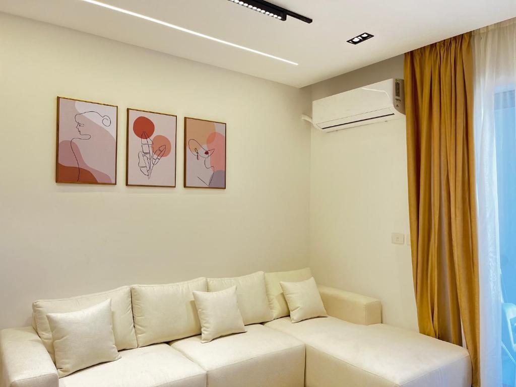 a white couch in a living room with paintings on the wall at Snow light 2BDR , Madinaty in Madinaty