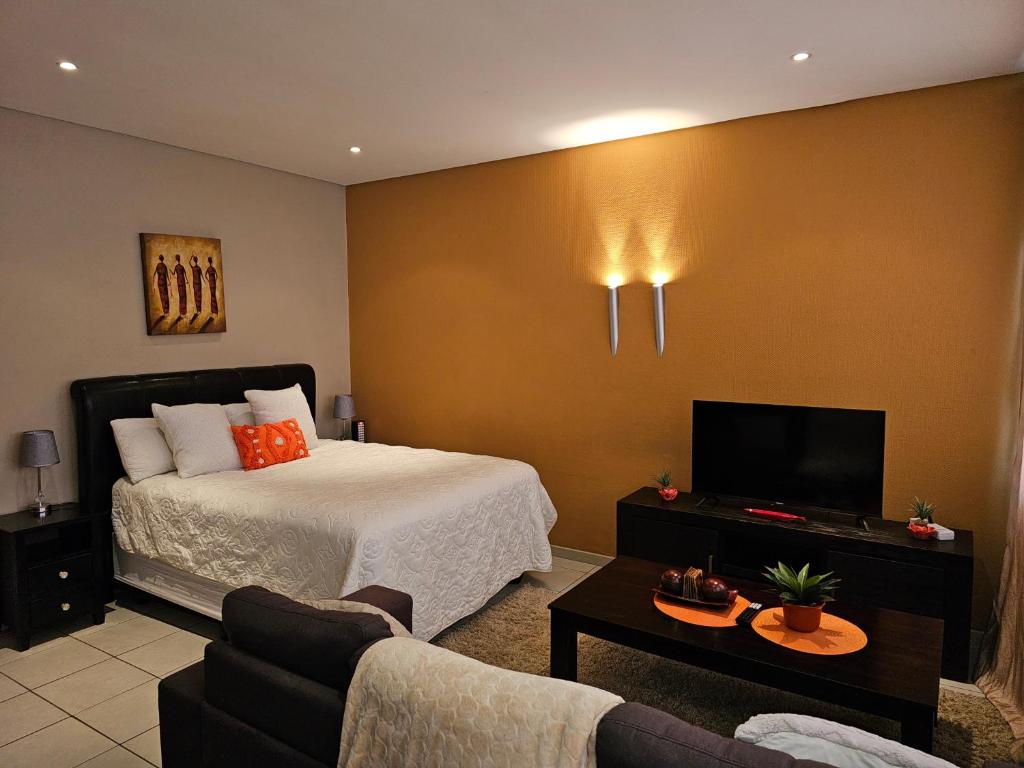 a hotel room with a bed and a tv at The Orange Corner II in Johannesburg