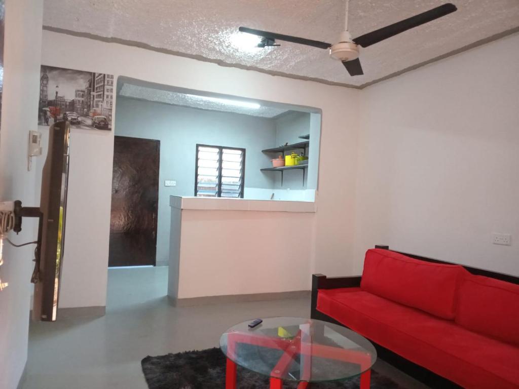 uma sala de estar com um sofá vermelho e uma mesa em The Truenorth apartments chitiri em Ukunda