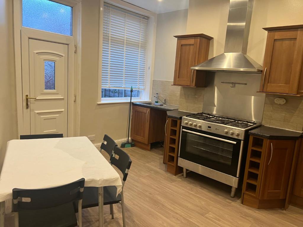 a kitchen with a stove and a table with chairs at Dairy House in Oldham