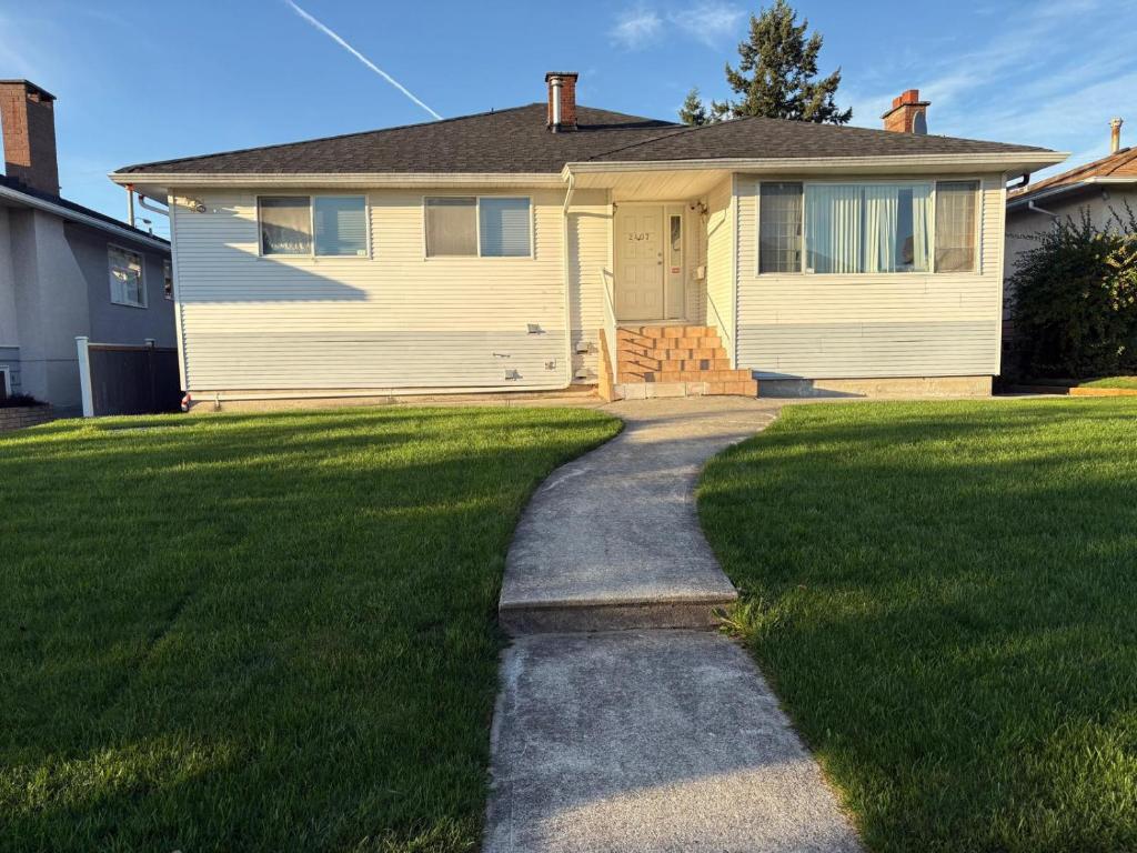 a house with a grassy yard with a sidewalk at Vancouver Business & Family Stay - Downtown 15 Min, Free Parking & Fast Wifi in Vancouver