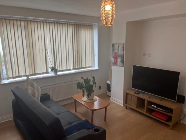 a living room with a couch and a flat screen tv at Stockley Apartments - Central in West Drayton