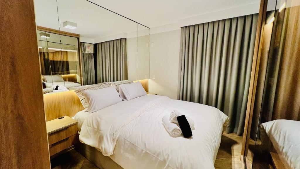 een slaapkamer met een groot wit bed en een spiegel bij Flat Luxo Jardins com Piscina, Vaga e serviços in Sao Paulo