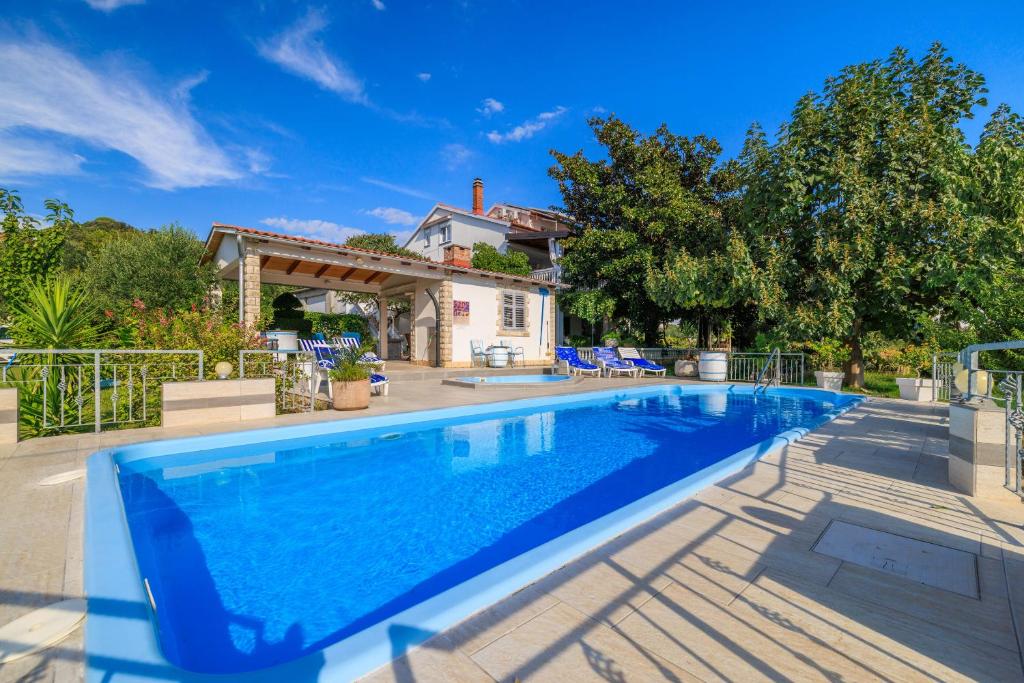 a large swimming pool in front of a house at Apartments Ankica in Kampor