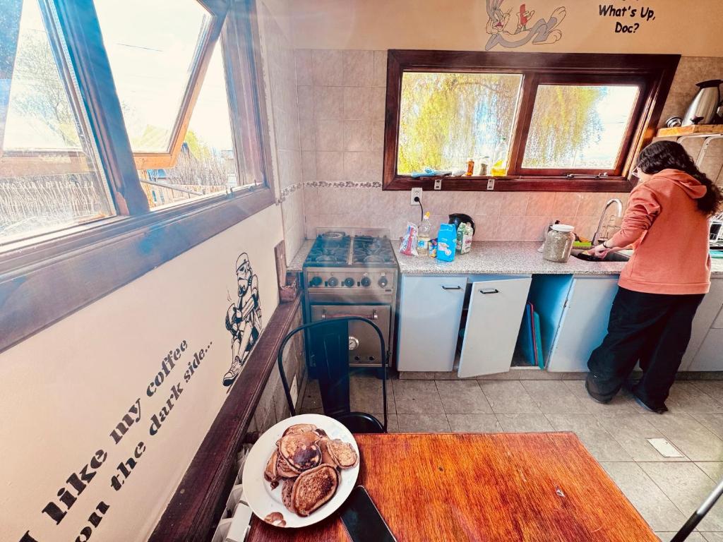a woman standing in a kitchen preparing food at Cabañas y Hostel I Keu Ken in El Calafate