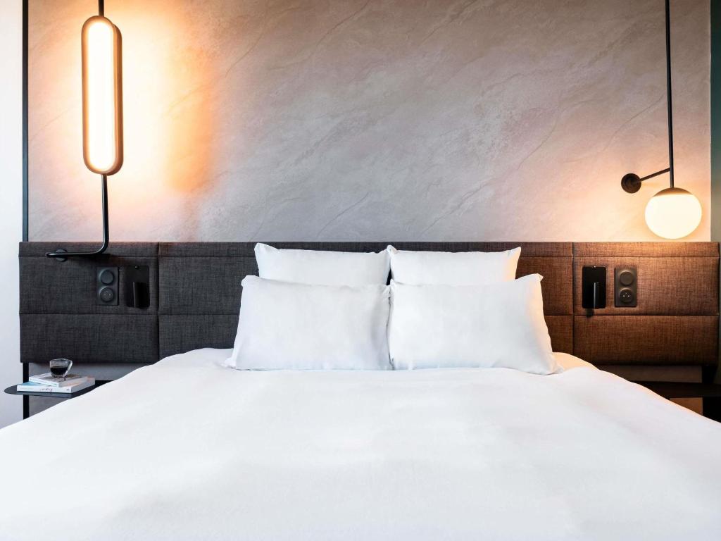 a bed with white sheets and pillows in a room at Novotel Atria Nimes Centre in Nîmes