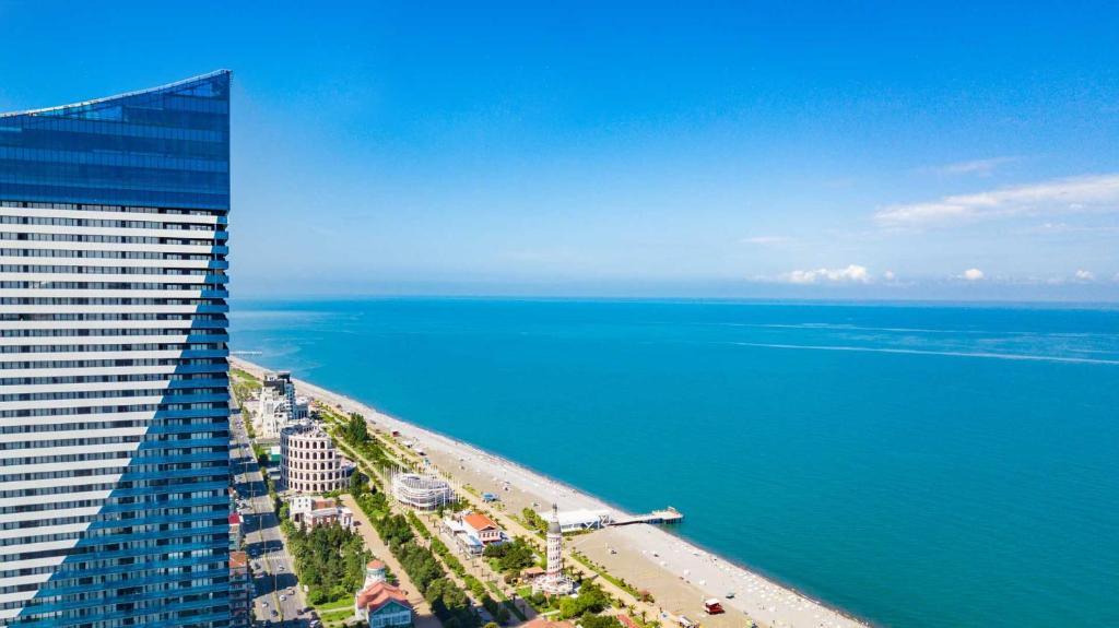 a tall building next to a beach and the ocean at Panorama Luxury SeaView in Batumi