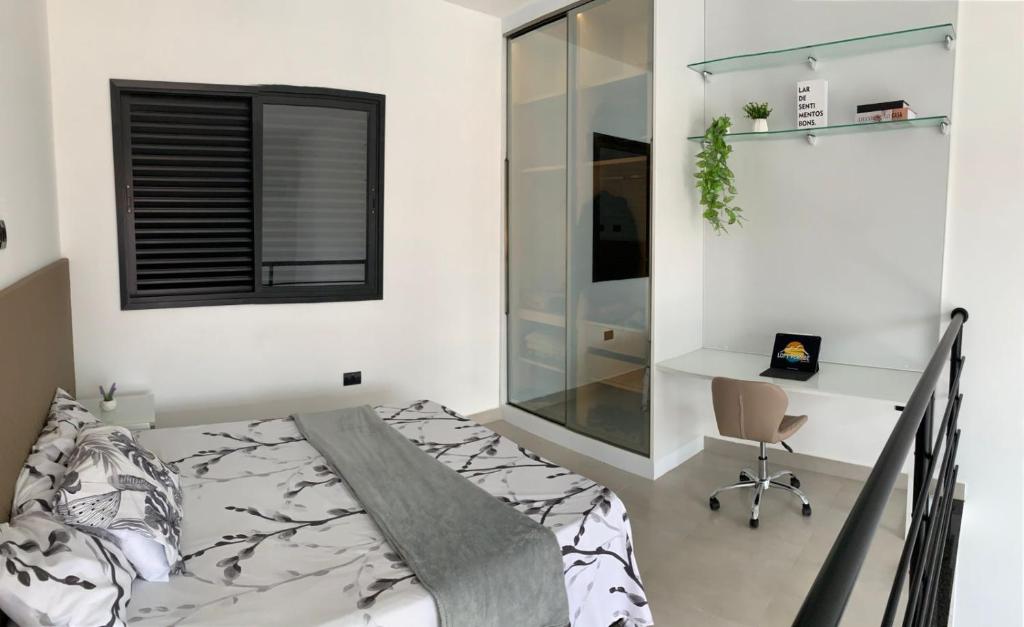 a bedroom with a bed and a desk and a chair at Loft de luxo em Peruíbe, 3 minutos da praia in Peruíbe