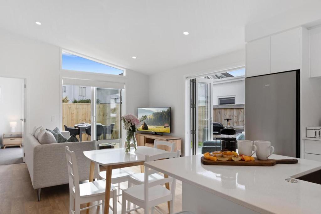 a kitchen and living room with a table and chairs at Perfect Papamoa Beach Bach in Papamoa