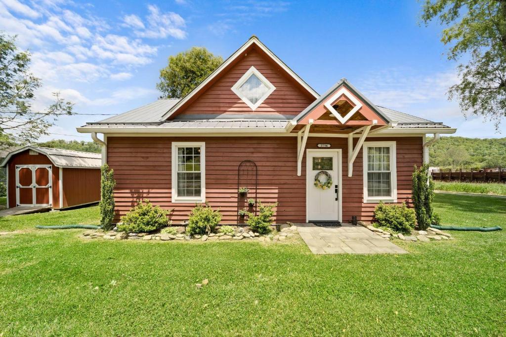 ein rotes Haus mit einer weißen Tür im Hof in der Unterkunft Broadstone Cottage in Banner Elk