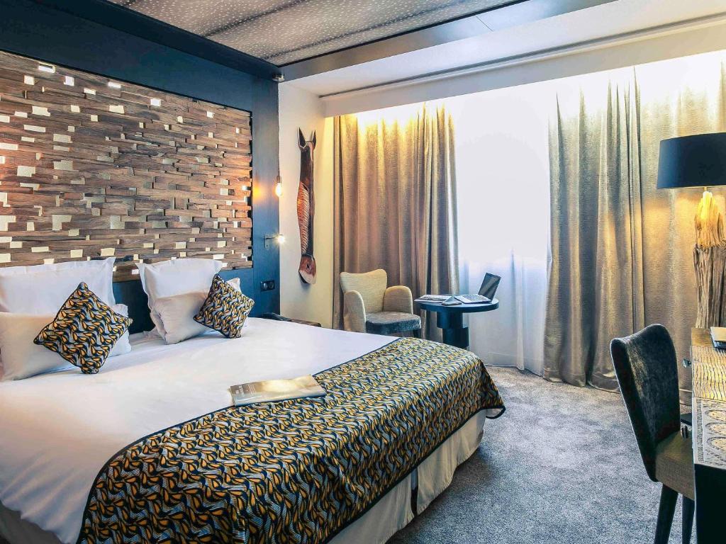 a hotel room with a large bed and a desk at Mercure Bordeaux Aéroport in Mérignac