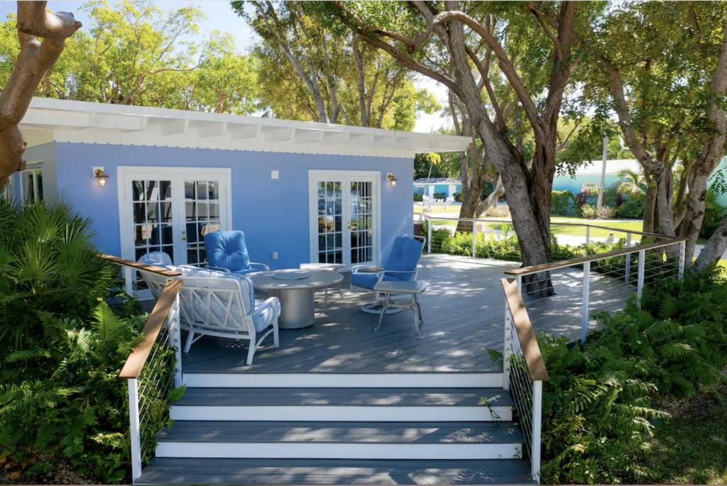 a blue house with a table and chairs on a deck at Charming Bayfront Cottage in Heart of Islamorada with Pool, Dockage, Beach, Kayaks & More in Islamorada