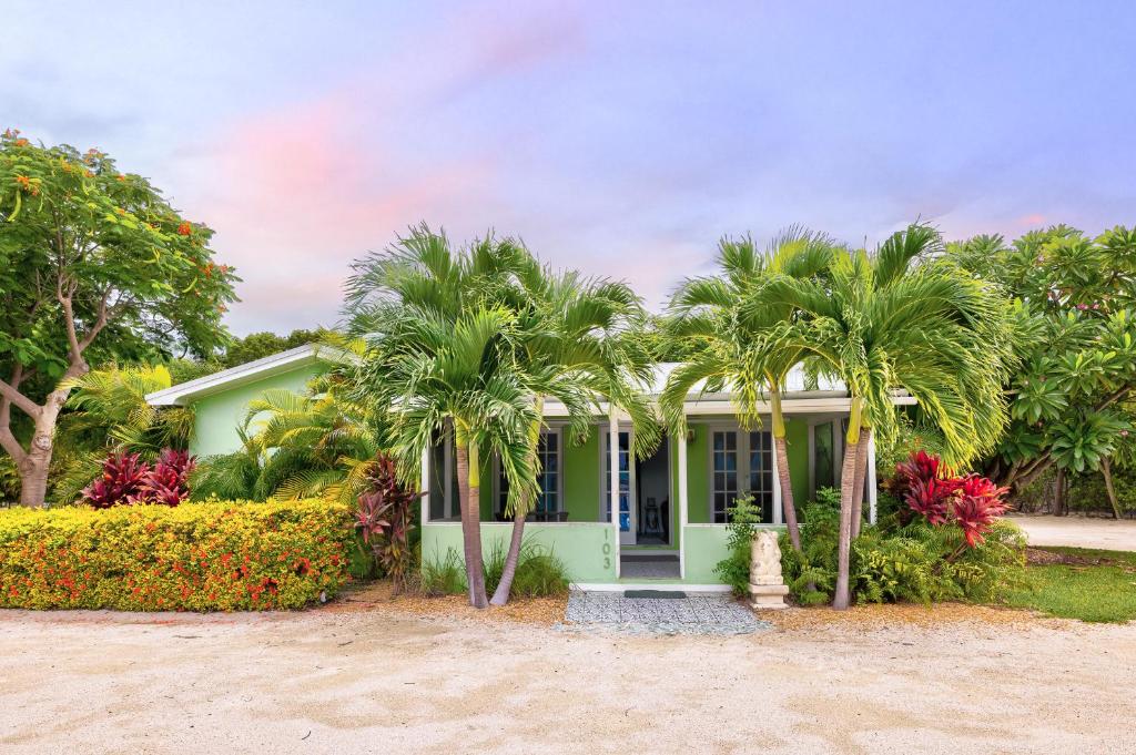 a green house with palm trees in front of it at Private Cottage on Bayfront Estate with Pool, Beach, Dockage, Kayaks and More in Islamorada