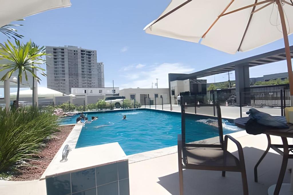 einen Pool mit einem Tisch und einem Sonnenschirm in der Unterkunft 1102 apto 2 Qtos-Wi-Fi-Piscina-Verão-Varanda-Vista in Ilha da Restinga