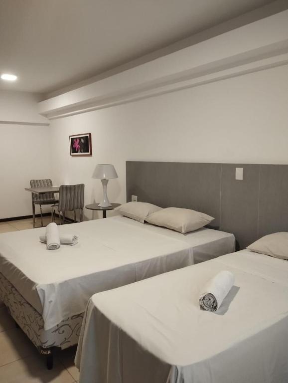 two beds in a room with a table and chairs at Celita Franca - WS Urban in Feira de Santana