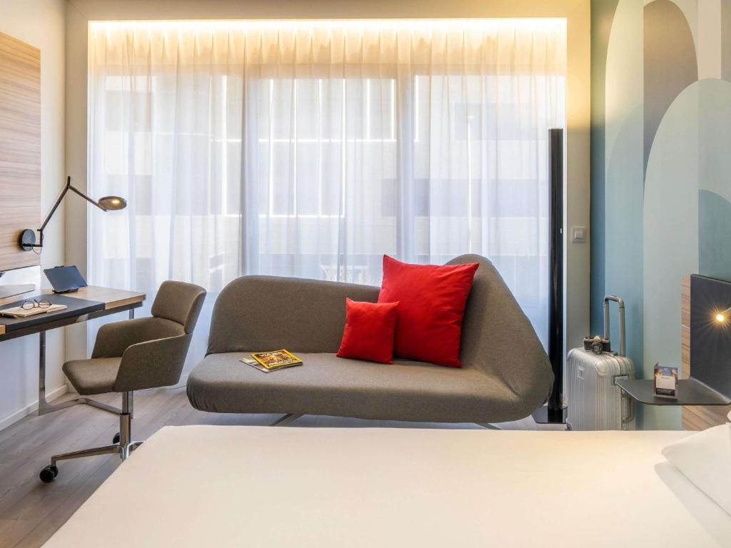 a living room with a couch with two red pillows at Novotel Campo De Las Naciones in Madrid