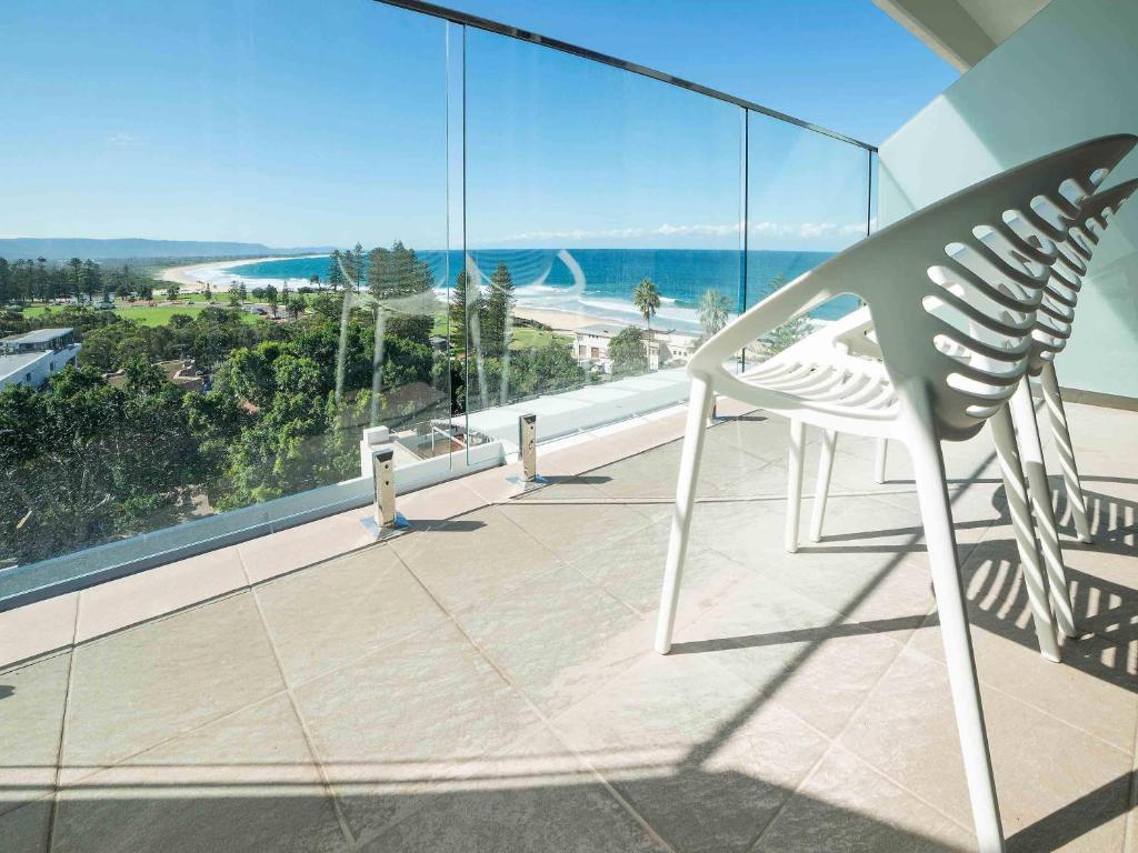 Una silla en un balcón con vista al mar. en Novotel Wollongong Northbeach, en Wollongong