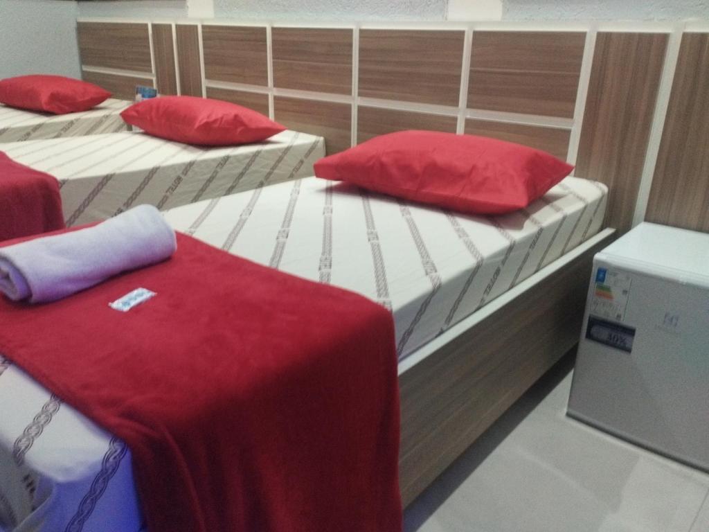 two twin beds with red pillows in a room at Hotel Progresso Itaquera - Próximo Arena Corinthians in Sao Paulo