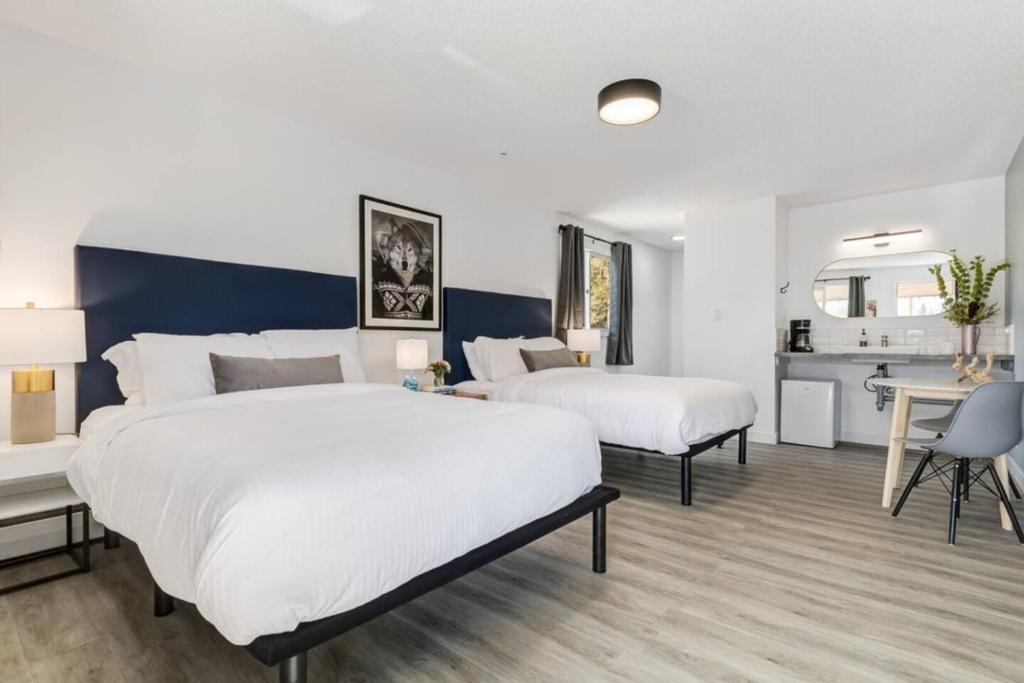 a hotel room with two beds and a desk and a table at Gateway Suites Perfect Escape to explore Banff in Canmore