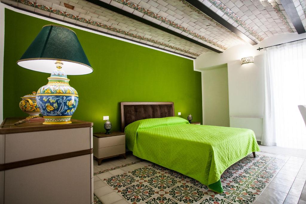 een groene slaapkamer met een bed en een groene muur bij Palazzo Pagliaro in Santo Stefano di Camastra