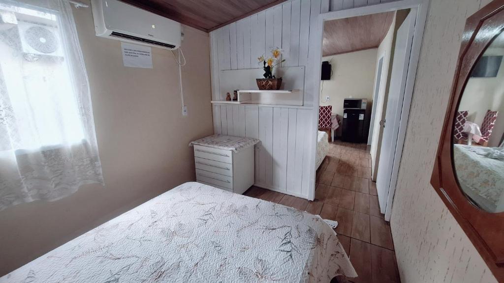 um pequeno quarto com uma cama e uma janela em KITNET k1 em TORRES-RS - Na mais bela praia Gaúcha - 2 quartos - Frigobar - micro-ondas - banheiro - ar condicionado split - TV smart 32' - Wi-Fi - Anfitriã Superhost no BnB em Torres