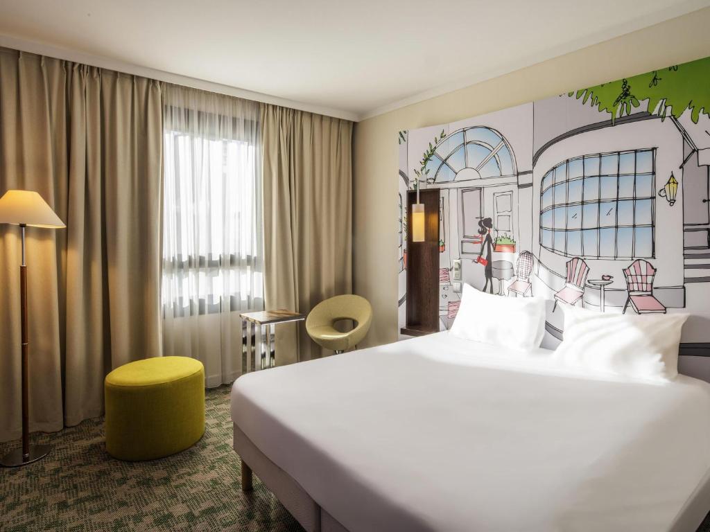 a hotel room with a large bed and a painting on the wall at ibis Styles Evry Courcouronnes Hotel and Events in Evry-Courcouronnes