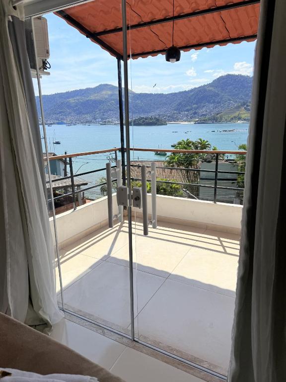 a room with a balcony with a view of the water at Apartamentos com vista para o Mar - Mirante do Marinas in Angra dos Reis