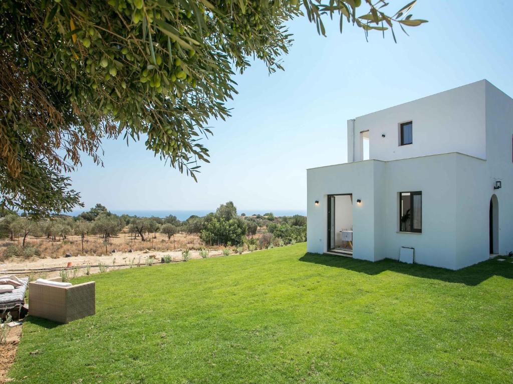 a white house on a green lawn with a tree at Secluded Villa with Panoramic Sea View in Rhodes Town