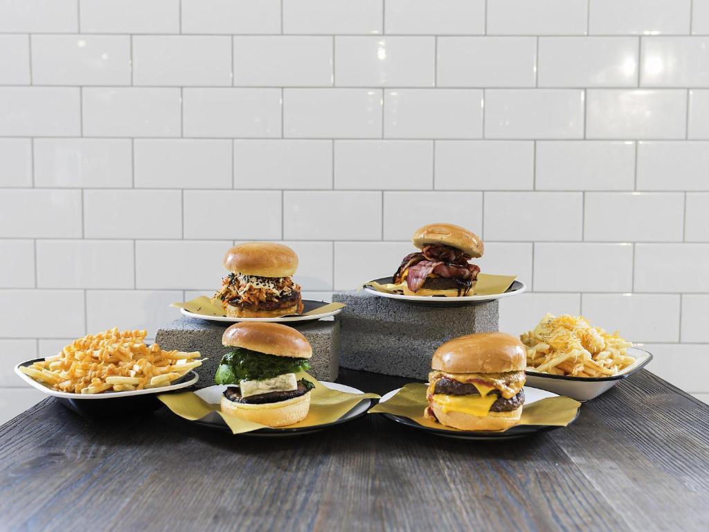 four plates of different types of burgers and french fries at Novotel Sydney Olympic Park in Sydney