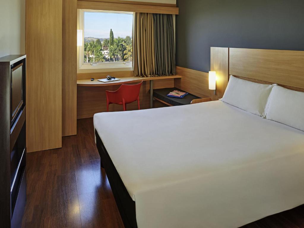 a bedroom with a bed and a desk and a window at ibis Sorocaba in Sorocaba