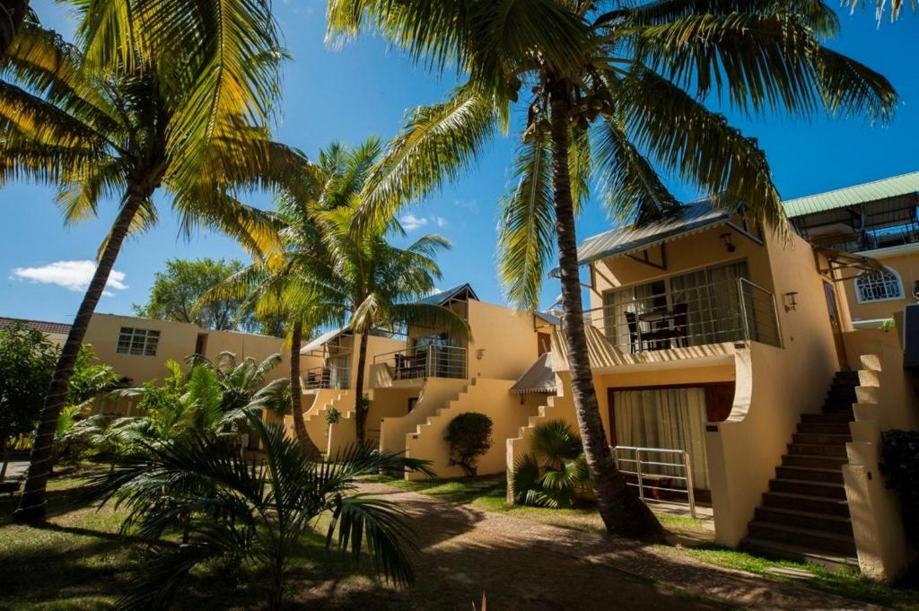 a house with palm trees in front of it at Manisa Hotel in Flic-en-Flac