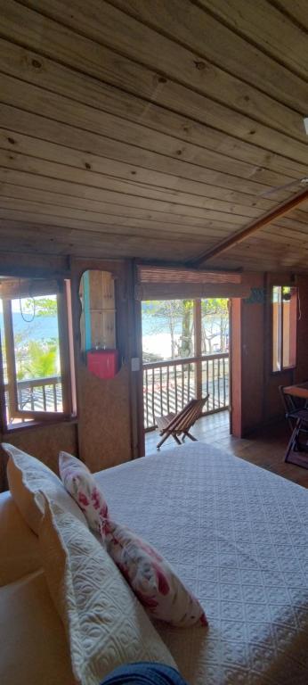 a bedroom with a bed in a room with windows at Suite Shambhala Ideal para Casal Beira Mar entre Paraty e Ubatuba in Ubatuba