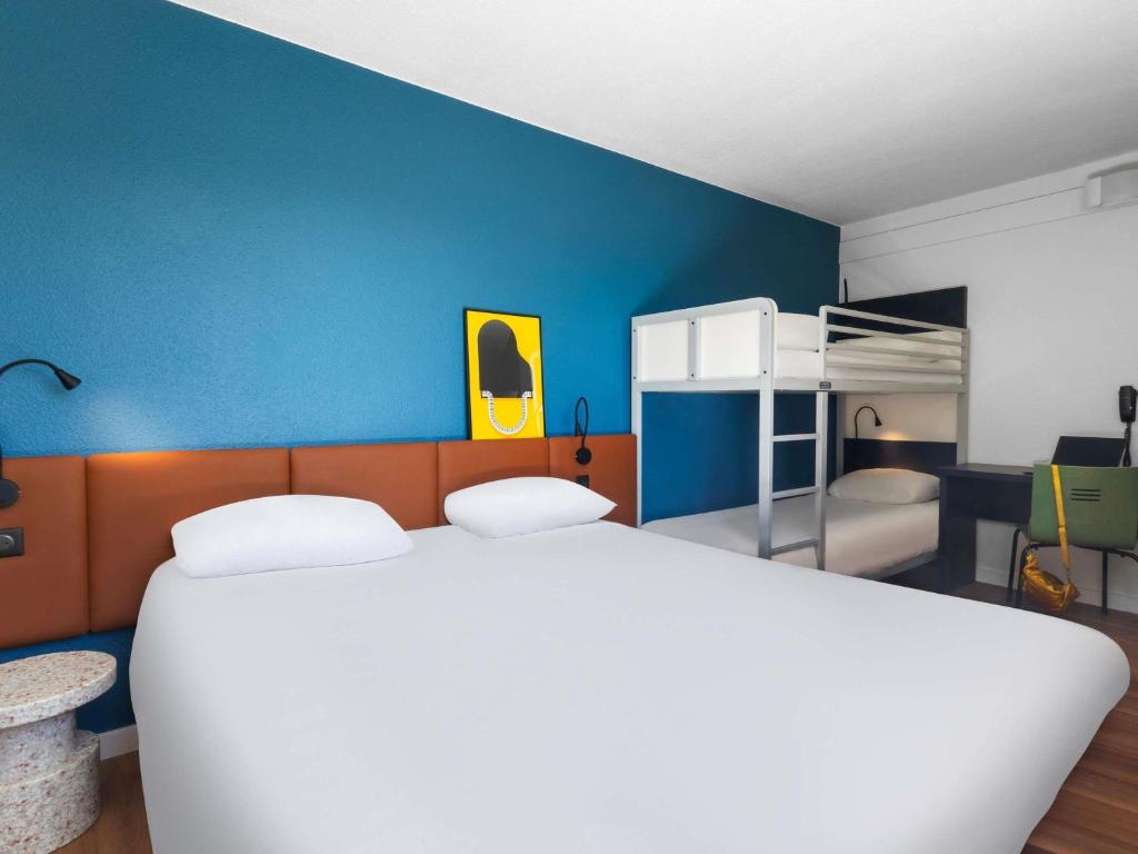 Un dormitorio con una cama blanca y una pared azul. en ibis Auch, en Auch