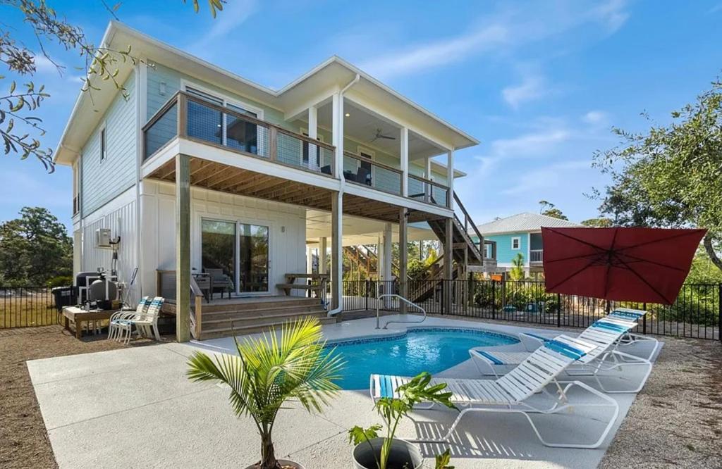 a home with a swimming pool and two chairs and a house at The Repose at Seven One Seven in Saint George Island