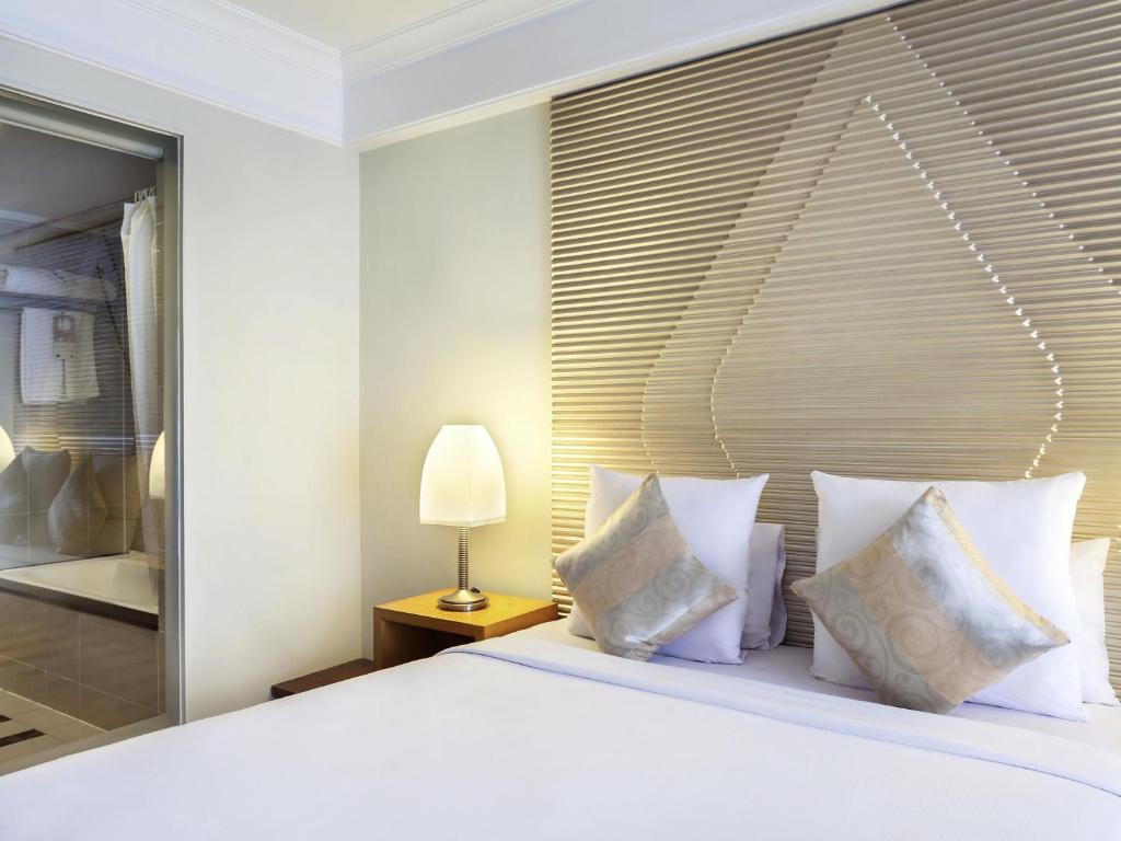 a bedroom with a large white bed with pillows at Novotel Semarang in Semarang