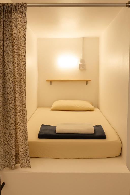 a bed in a room with a curtain and a light at Sunset Homestay - Backpacker Hostel Self Checkin in Kuching