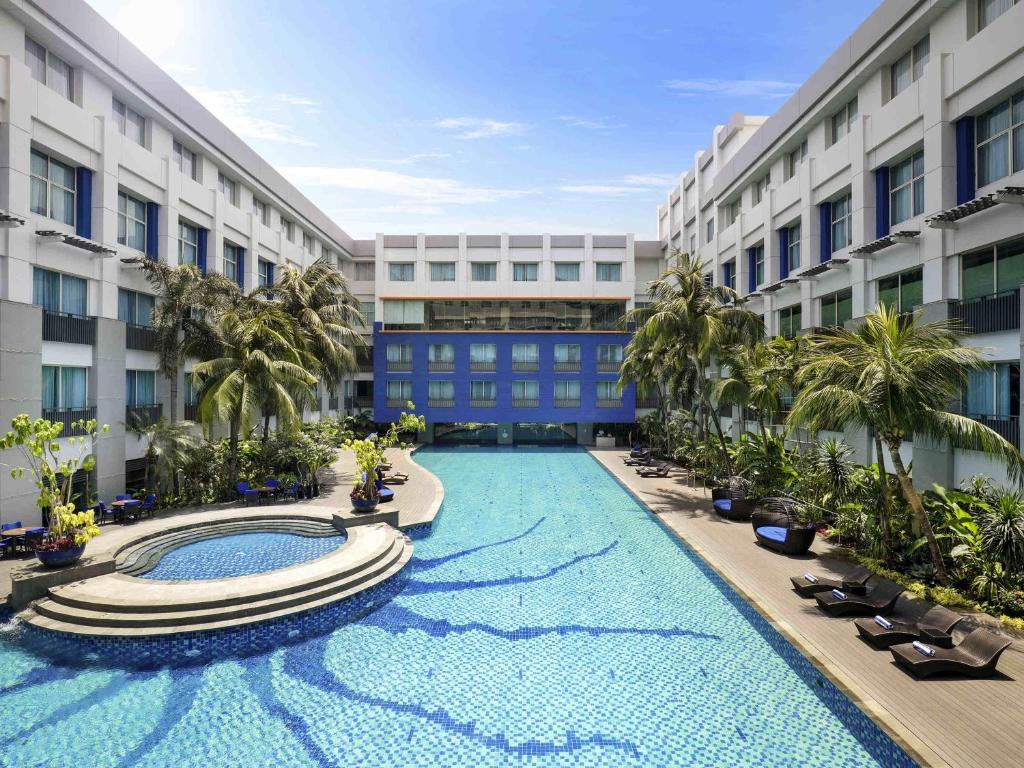 a large swimming pool in the middle of a building at Novotel Jakarta Mangga Dua Square in Jakarta