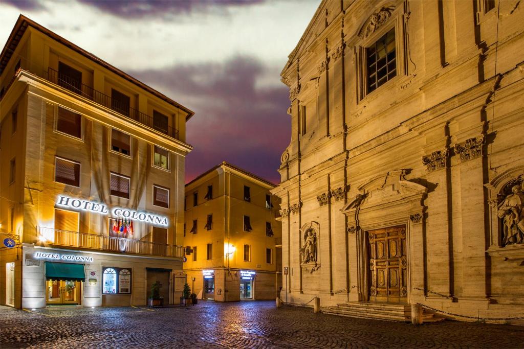 een stadsstraat 's nachts met twee gebouwen bij Colonna Hotel in Frascati