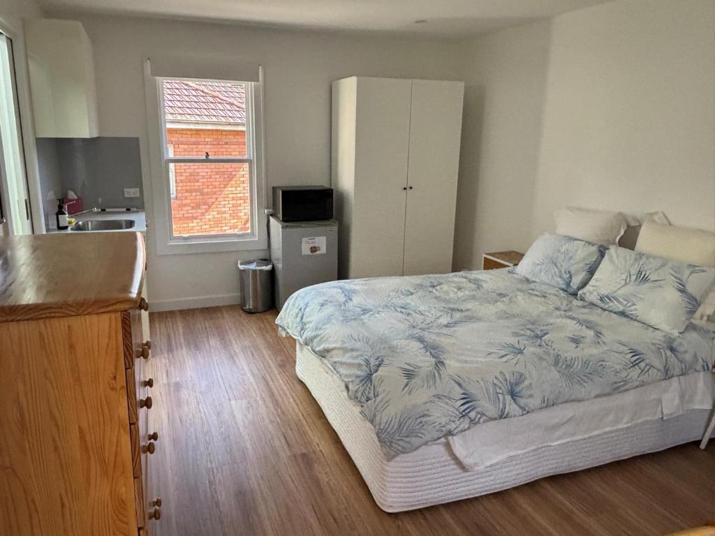 a bedroom with a bed and a kitchen with a window at Studio granny flat in Sydney